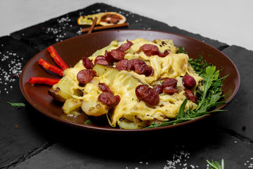 Fried potatoes under hot cheese on a black art background
