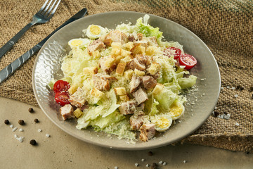 Caesar salad with croutons, parmesan, chicken, egg in a white stylish bowl. Restaurant serving. Selective focus, rustic background