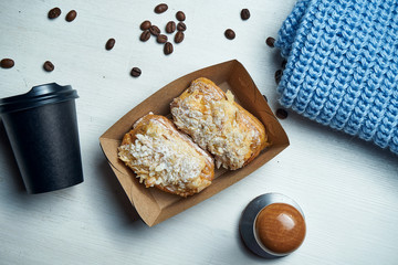Two classic eclairs with with almond topping and custard in a box on a white background. Tasty coffee dessert. Top view, flat lay food