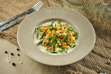 Healthy food - steamed vegetables in a creamy sauce in a ceramic bowl on rustic background. Tasty lunch. Close up