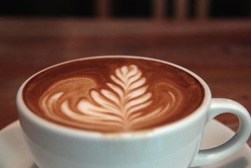 Hot Latte coffee in white cup on the table at coffee cafe backdrop - Drink and Relax chill out in the co working space cafe 