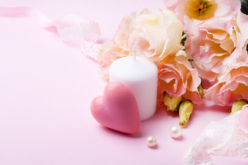 Beautiful pink flowers, candle and pink heart on a pink background