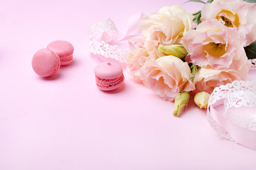 Beautiful pink eustoma flowers and macaron on a pink background