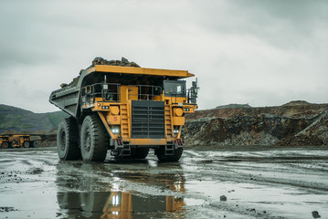 Dump trucks riding on the background of the mine.