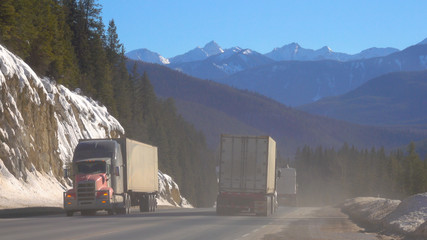 Freight trucks transport containers across the picturesque Banff National Park.