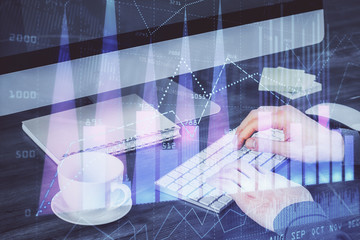 Multi exposure of graph with man typing on computer in office on background. Concept of hard work.