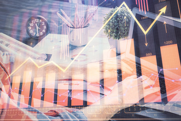 Double exposure of stock graph with businessman typing on computer in office on background. Concept...