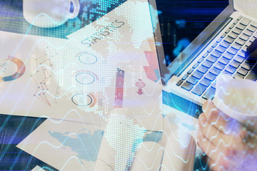 Double exposure of stock graph with businessman typing on computer in office on background. Concept...