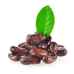 Heap of roasted cacao beans with green leaves isolated on a white background.