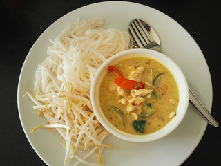 Green curry serve with rice noodle and fresh bean sprout in white ceramic dish on dark table