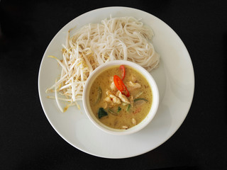 Green curry serve with rice noodle and fresh bean sprout in white dish on dark table