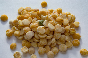 grains of scattered yellow-white dry peas in an enlarged form lie on a white sheet