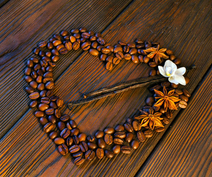 Heart Made Of Coffee Beans With Flower And Vanilla Sticks On A Wooden Table.