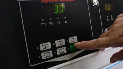 pressing the button to select the washing mode with a woman's hand