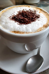 A cup of coffee in a white cup on wooden background.