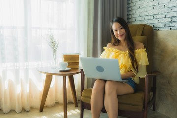 Portrait young asian woman sit on chair using laptop computer with coffee cup and book