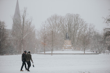 couple walking in snowy park long shot amsterdam 