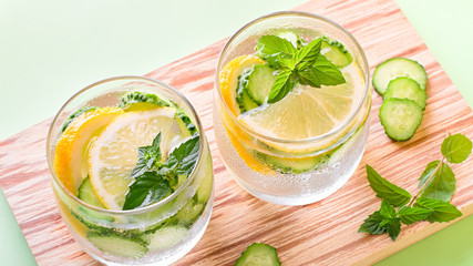 Healthy refreshing summer cocktail or mocktail without alcohol with lemon and cucumber. Summer detox drink on fresh green background, healthy living, top view
