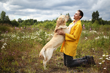 Happy man embracing dog on forest meadow