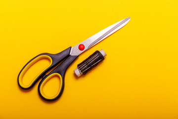 Flat lay of colored thread rolls and Scissors for sewing yellow background. Sewing and needlework concept. Tools for sewing and handmade: thread, scissors.