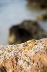 Close up of two wedding ring on wet rocks on the beach, copy space