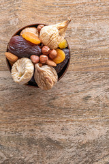 Dried fruits and nuts on wooden background. Raw food diet. Free space for text.
