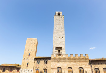 Fototapeta premium Rognosa tower and the Palace of the Podesta in the historic centre of San Gimignano (Piazza Duomo), province of Siena, Tuscany, Italy