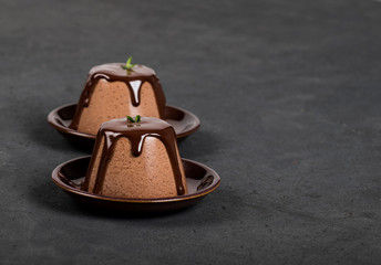 Italian dessert Panna cotta with chocolate sauce on a dark background