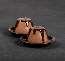 Italian dessert Panna cotta with chocolate sauce on a dark background