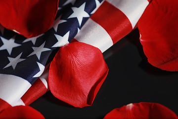 American flag and rose flower on the table. Symbol of the United States of America and red petals. Patriotism and memory.