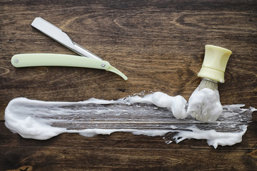 Shaving accessories on a wooden texture background. Tools. Disposable shaving machine, brush, foam and hazard razor.