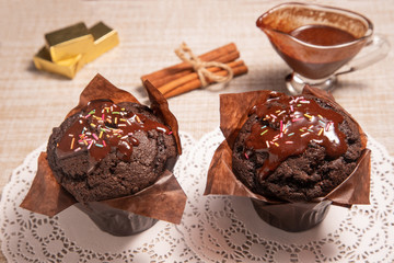 two chocolate muffins on a table with hot chocolate