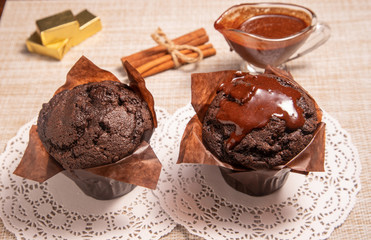 two chocolate muffins on a table with hot chocolate