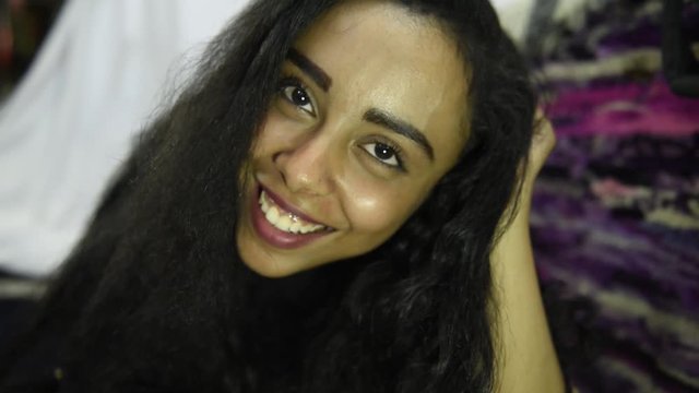 Beautiful middle eastern girl laugh look at camera while lying in  bed at home