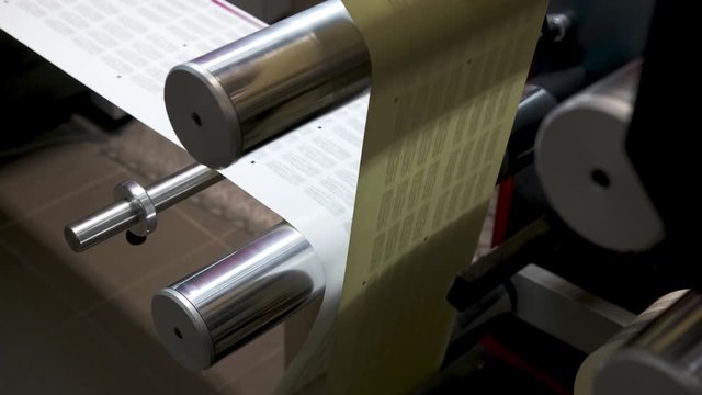 rows of shafts of large offset printing press. moving polymer label conveyor typography facility and flexographic printing