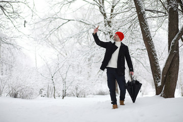 A man on a walk in the park. Young man with in the winter snowfall.