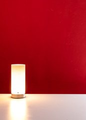 Bright warm light on a white clean desk with a modern red wall background