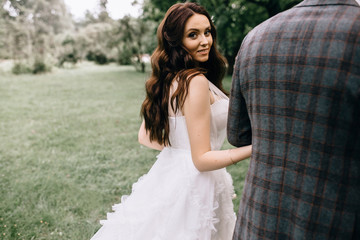 Naklejka premium Beautiful bride in fashion wedding dress on natural background.The stunning young bride is incredibly happy. Wedding day. .A beautiful bride portrait in the forest.