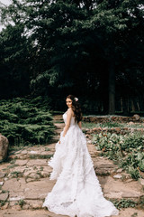 A beautiful bride stands with her back in her wedding dress. Dress with lace. The happy bride is spinning.