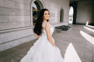 bride in a beautiful white and long dress on a background of  building