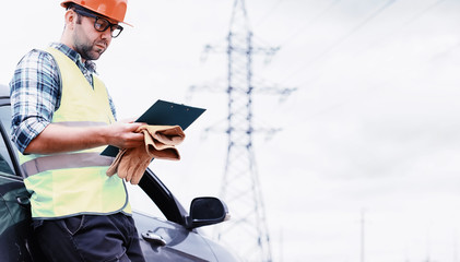 A man in a helmet and uniform, an electrician in the field. Professional electrician engineer...