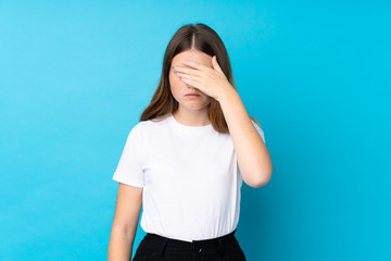 Ukrainian teenager girl over isolated blue background covering eyes by hands