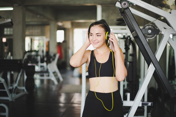 Beautiful women come to exercise in the gym and are relaxed by listening to music from headphones. She wears a sportswear.