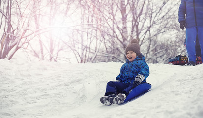 Children in the park in winter. Kids play with snow on the playground. They sculpt snowmen and slide down the hills.