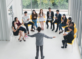 Asian Speaker male is speaking at seminars and workshops to the people in the meeting. By the participants of the seminar and training sitting round a semicircle. Top view.