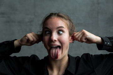 Young Woman Pulling Ears with Eyes Crossed and Tongue Sticking Out