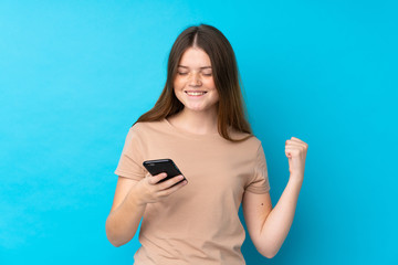 Ukrainian teenager girl over isolated blue background with phone in victory position