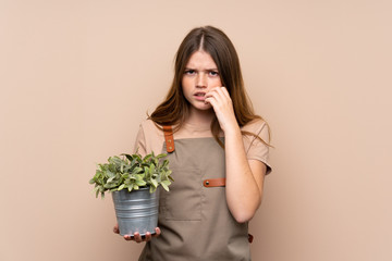 Ukrainian teenager gardener girl holding a plant nervous and scared