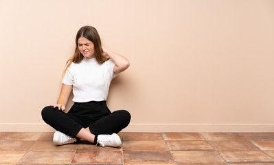 Ukrainian teenager girl sitting on the floor with neckache