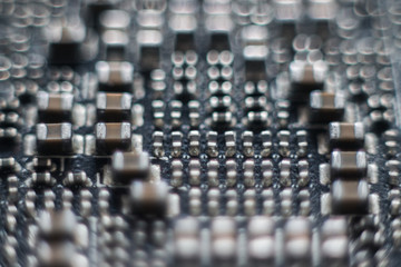 Close up macro on electronic system with integrated circuit chip and capacitors. Old board with dust